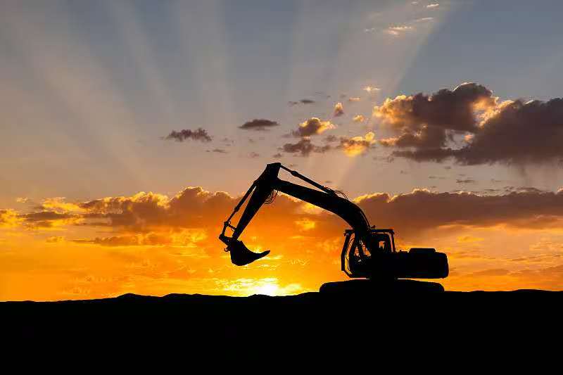 Excavator silhouette on a job site at sunset — earthmoving and infrastructure